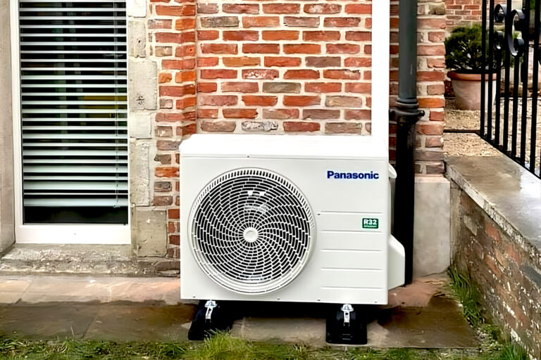 Panasonic buitenunit van een airconditioningsysteem naast een bakstenen muur.